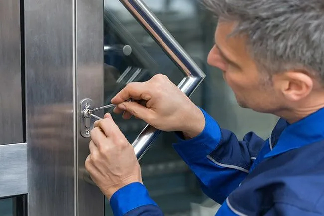 Commercial locksmith performing lock and key service for a business door
